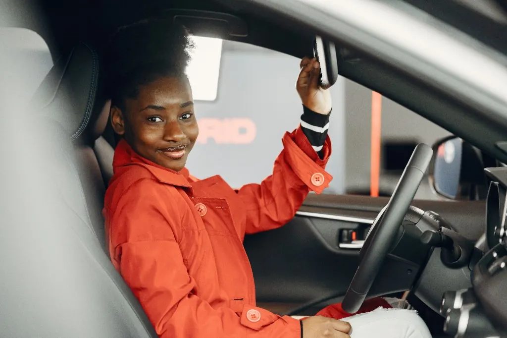 Confident student driver adjusting the rearview mirror